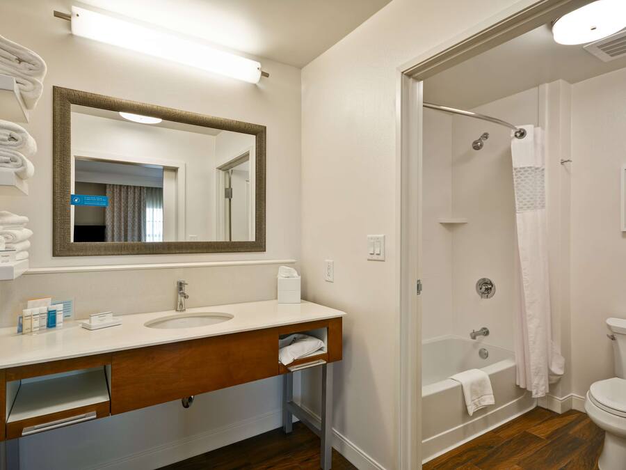 A bathroom with a sink, mirror, and shower area.