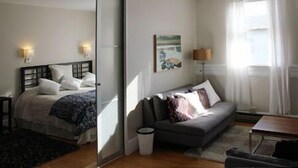 Un dormitorio con cama, sofá, lámpara y un cuadro en la pared.