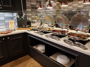 A buffet setup with various food items and utensils. - Hilton Garden Inn Savannah Historic District (Savannah)