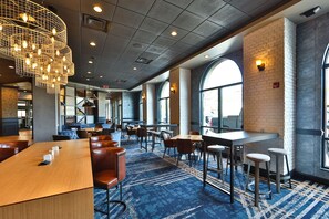A spacious restaurant with high ceilings, exposed brick walls, and large windows.