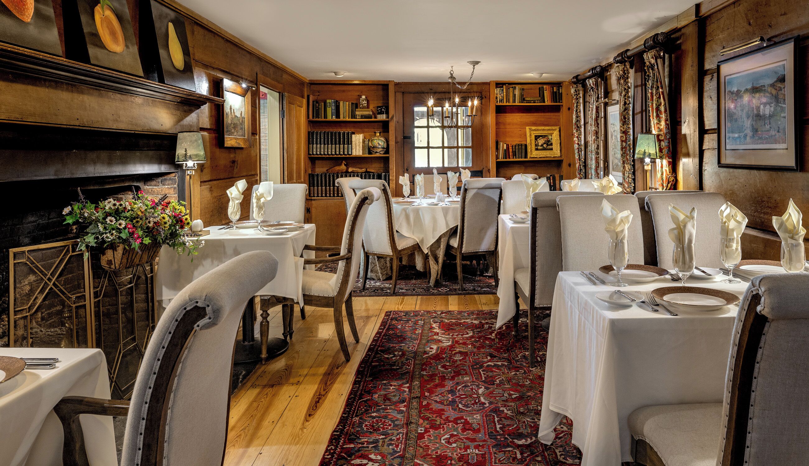 A dining area with multiple tables set for a meal, wooden walls, and a large window.