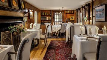 A dining area with multiple tables set for a meal, wooden walls, and a large window.