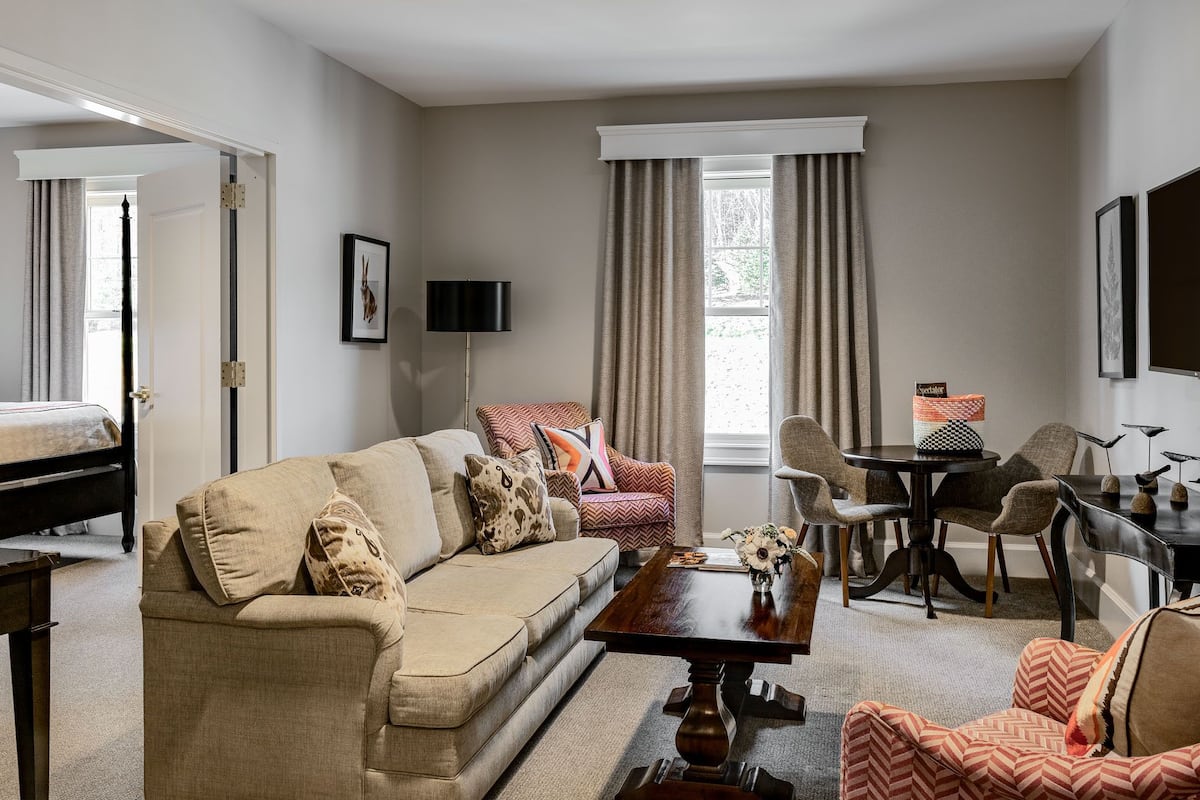 A living room with a sofa, armchairs, a coffee table, and a dining area with chairs and a table.