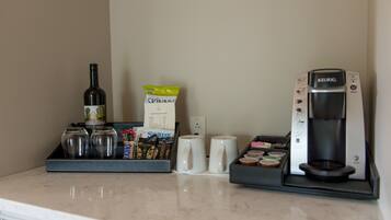 Una moka, una bottiglia di vino e un vassoio con cialde per il caffè e zucchero su un piano di lavoro della cucina.