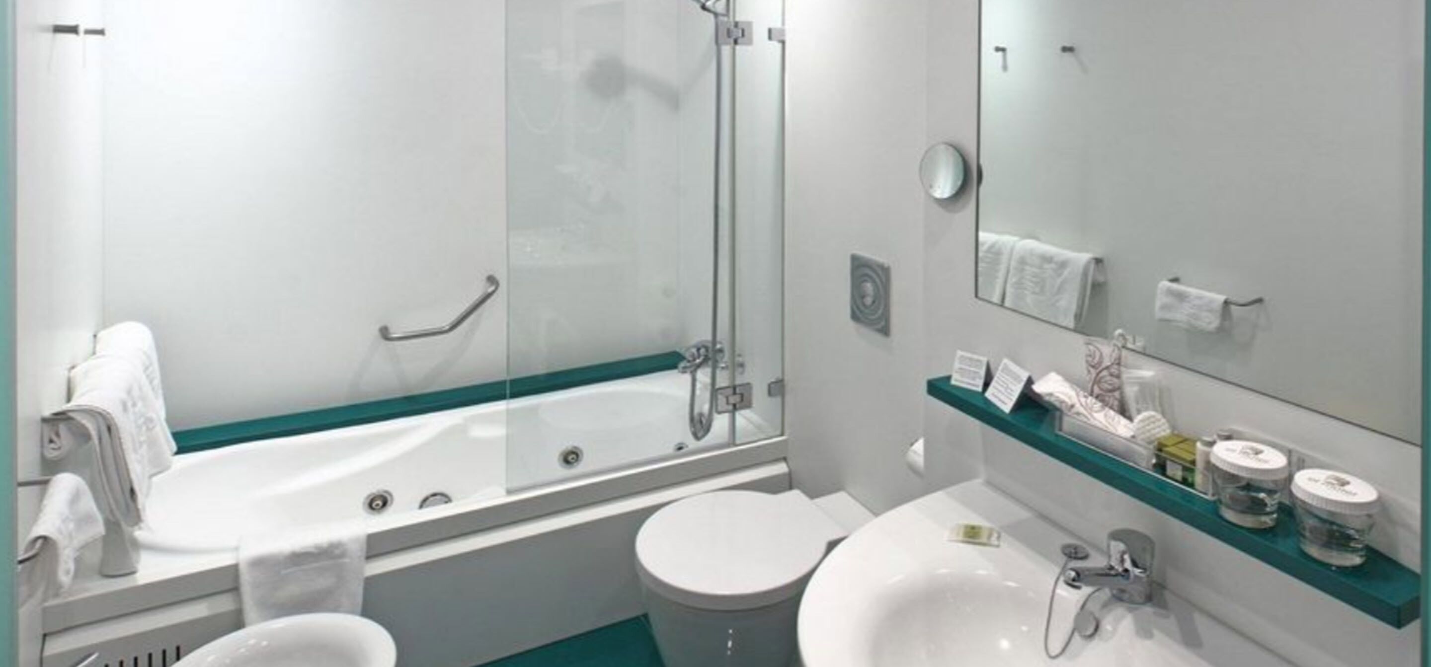 Un baño moderno con ducha de vidrio, un lavabo blanco y un espejo sobre el lavabo.