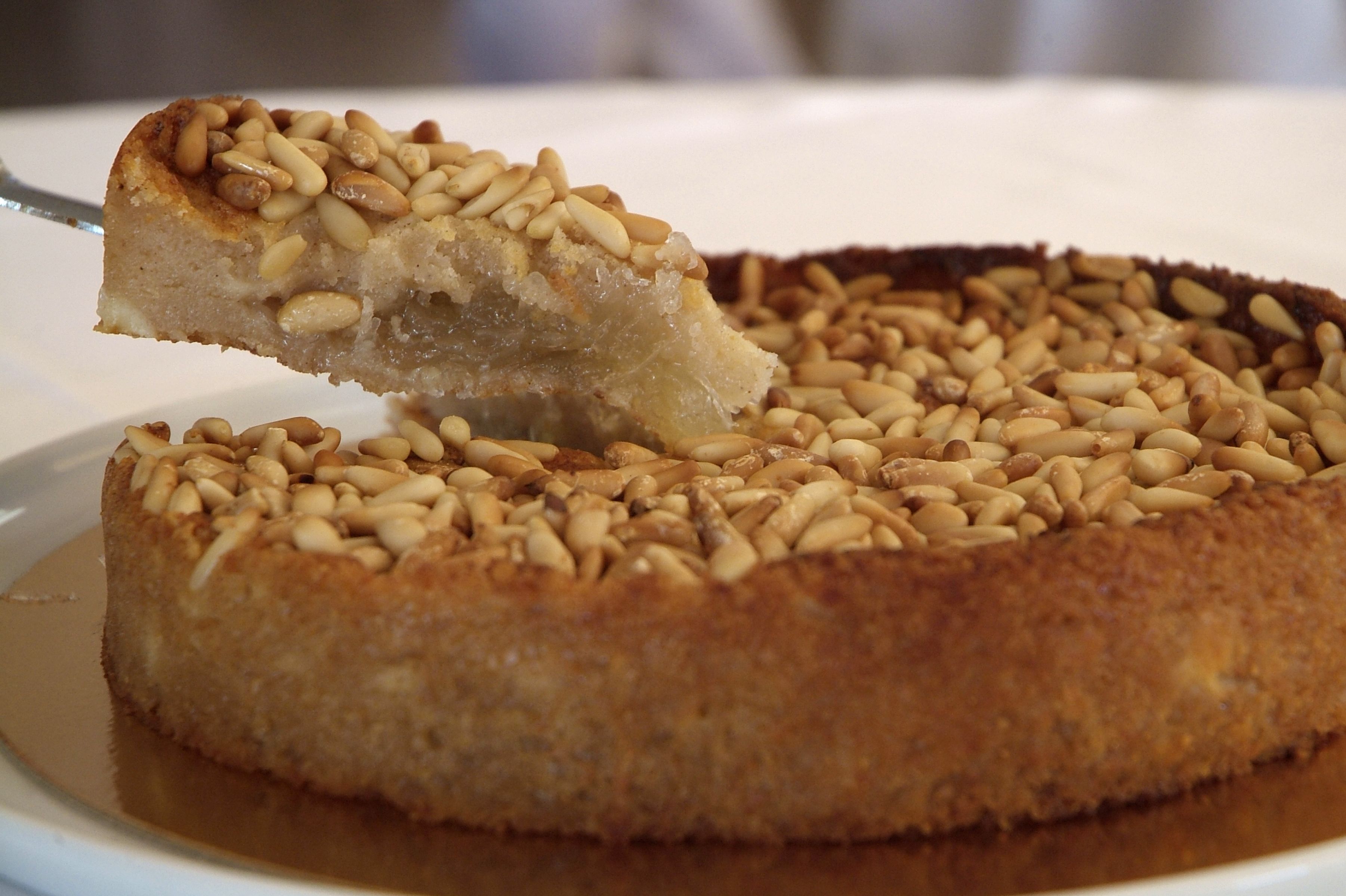 Un pastel redondo con corteza dorada y cobertura de piñones.