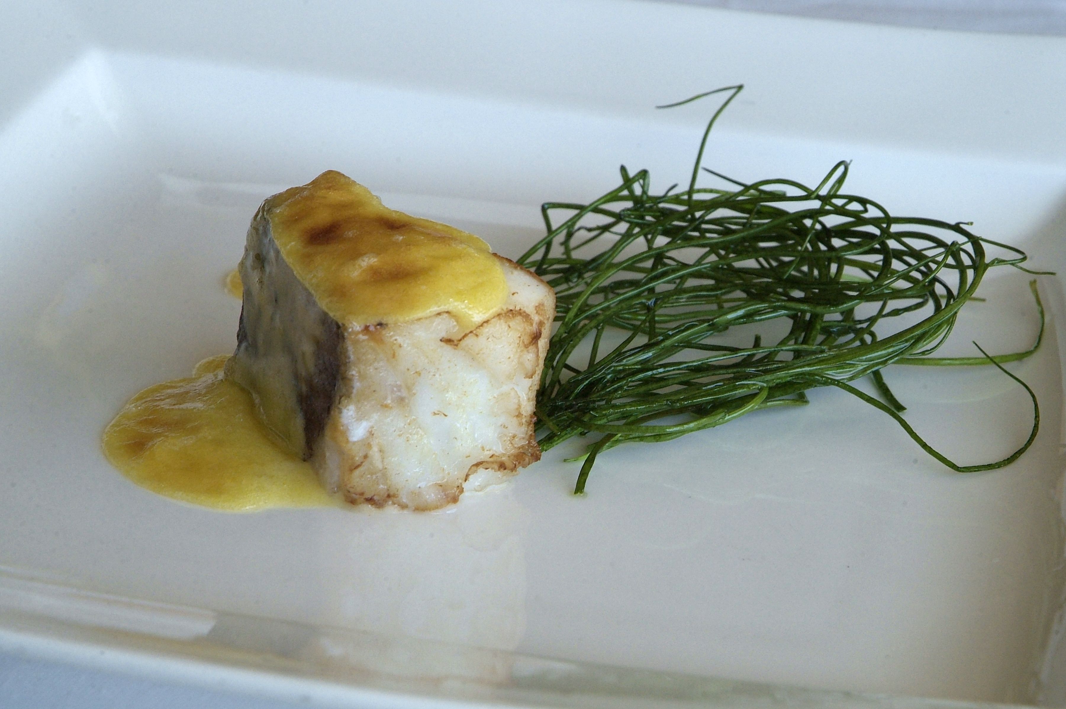 A dish with a golden sauce and green garnish on a white plate.