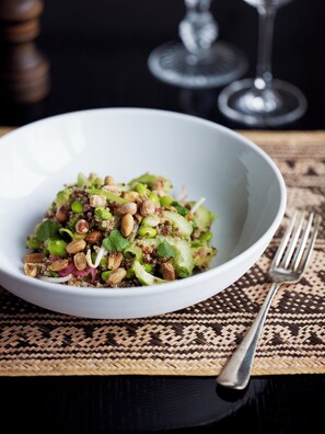 Eine Schüssel mit Salat, Nüssen und Grünzeug auf einer gewebten Unterlage.
