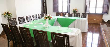 A conference room with a long table, chairs, and a green tablecloth.