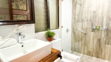 Un baño moderno con un lavamanos grande, un espejo y una ducha.