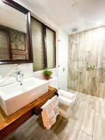 Un baño moderno con un lavamanos grande, un espejo y una ducha.