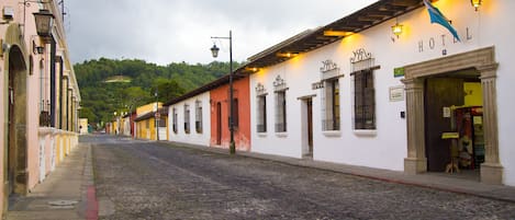 A cobblestone street lined with historic buildings, including a hotel with a sign.