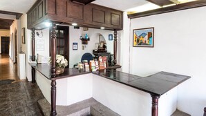 Un comptoir d’accueil avec un revêtement en bois foncé, un vase rempli de fleurs blanches et un tableau encadré accroché au mur.