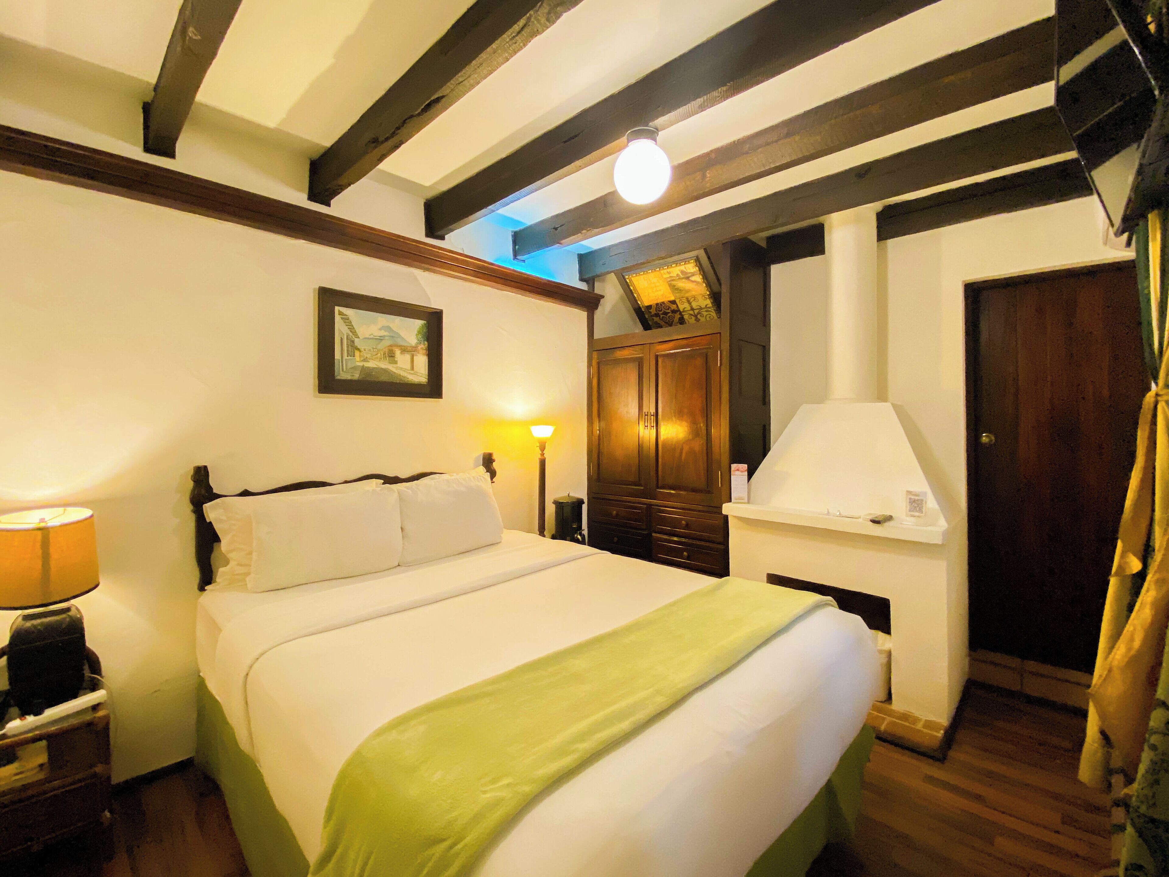 A bedroom with a bed, a nightstand, a lamp, a wardrobe, and a mirror.