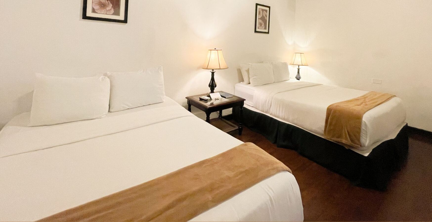 Ein Hotelzimmer mit zwei Betten, einem Nachttisch und zwei Wandlampen.