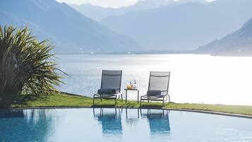 Una piscina al aire libre, sombrillas, sillones reclinables de piscina