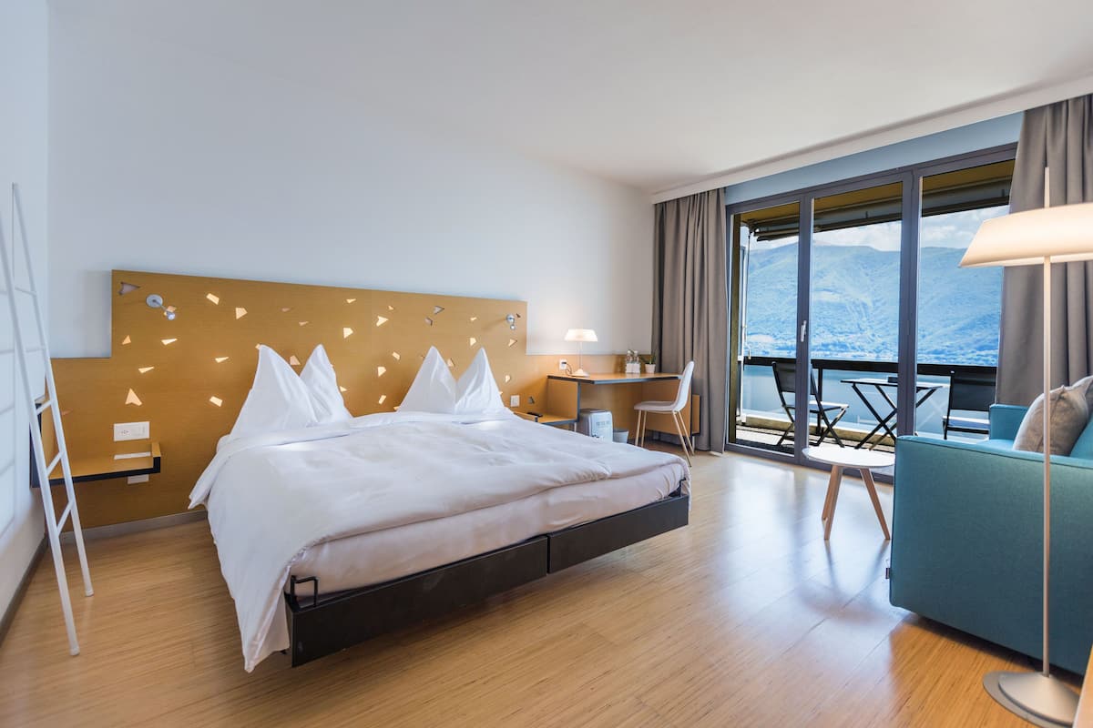 Una habitación de hotel moderna con cama, escritorio y balcón con vistas.
