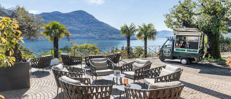 An outdoor seating area with wicker furniture and a view of a lake and mountains.