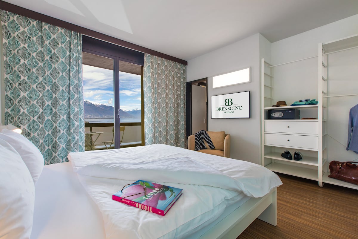 Habitación de hotel con cama, vistas a montañas, un armario y un cartel enmarcado en la pared.