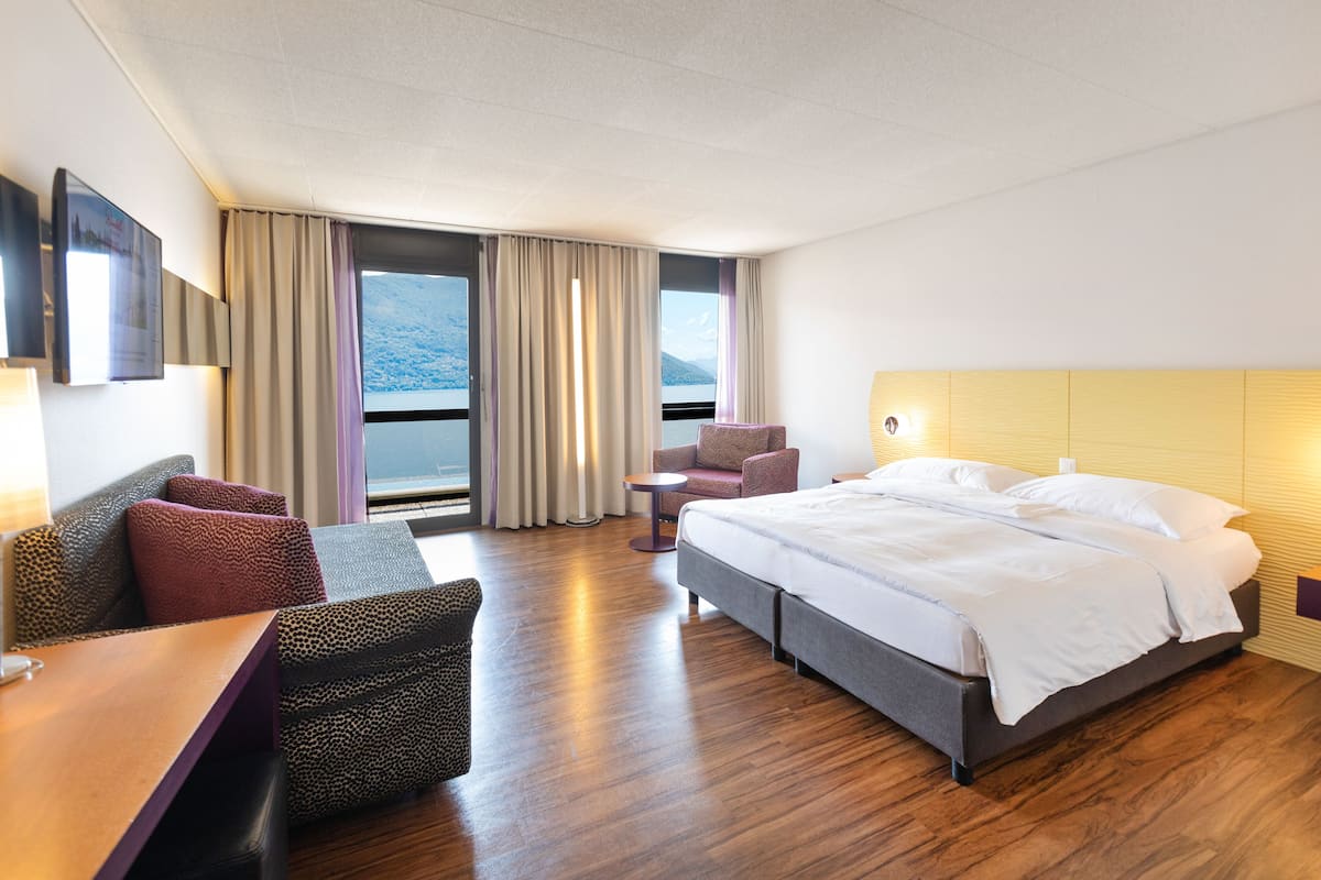 Una habitación de hotel con una cama, un sofá, una silla y una pequeña mesa.