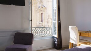 A bedroom with a bed, a chair, a desk, and a TV. - Hotel du Theatre (Lyon)