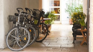 Bicycles parked against a wall, a wooden table with chairs, and potted plants in a hotel corridor. - Hotel Schlicker (Munich)