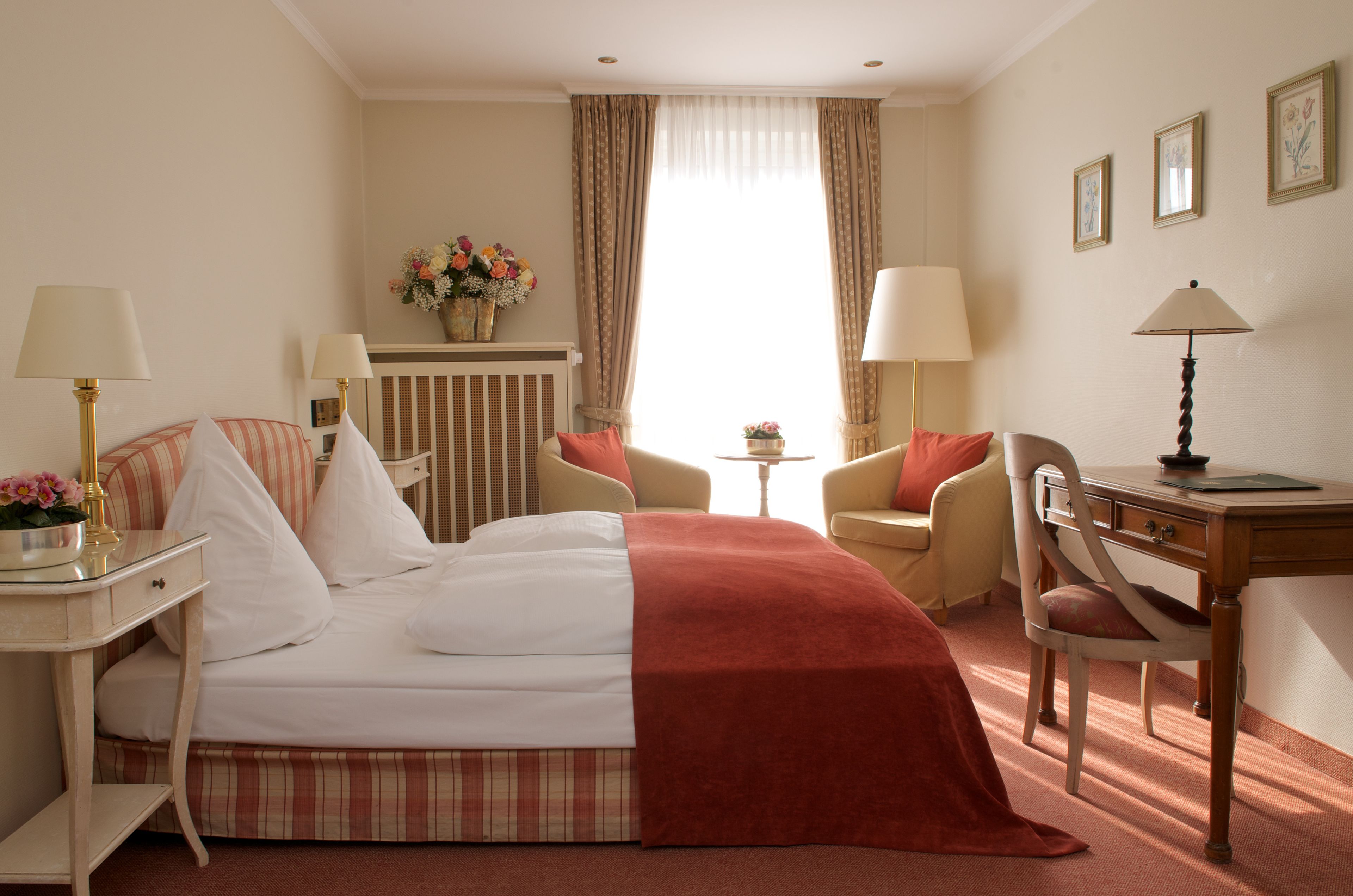Ein Hotelzimmer mit Bett, zwei Stühlen, einem Schreibtisch und einer Lampe.