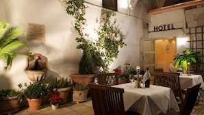 A hotel courtyard with potted plants, a fountain, and tables set for dining. - Hotel Schlicker (Munich)