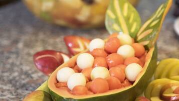 Une salade de fruits servie dans une demi-papaye évidée, posée sur un plan de travail en granit.