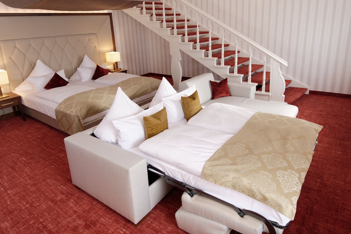 Habitación de hotel con dos camas, una escalera y una alfombra roja.