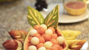 Un frutero con una disposición decorativa de frutas y un plato con fruta cortada.