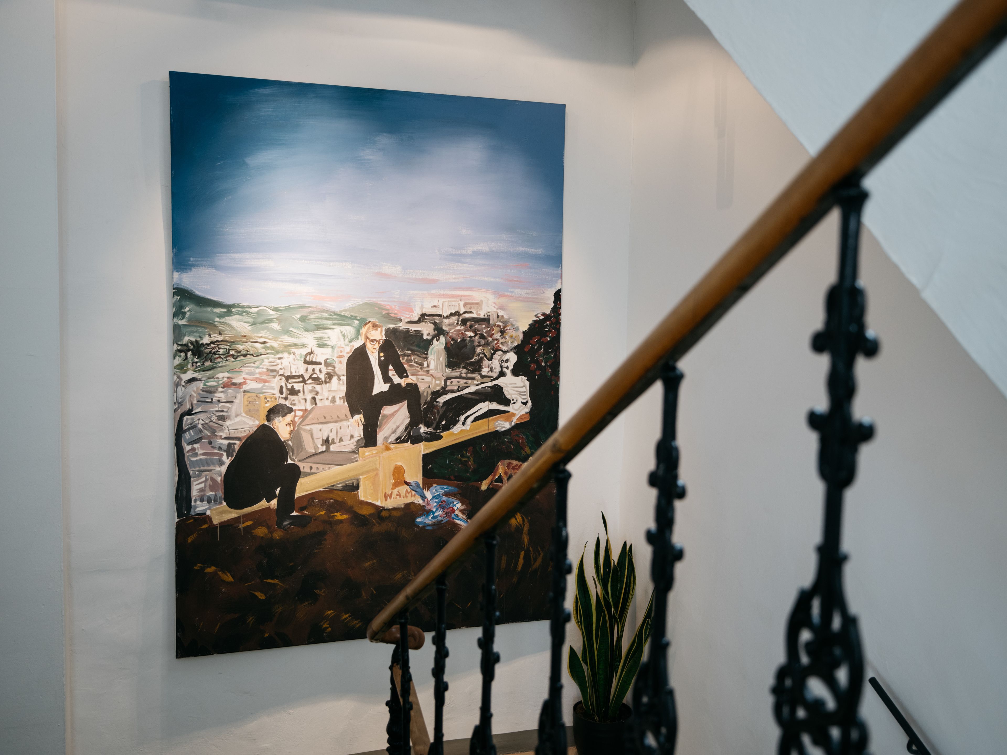 Ein großes Gemälde an der Wand, eine Treppe mit Geländer und ein Blumentopf.