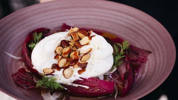 Un tazón de comida con cobertura cremosa, nueces y vegetales verdes.