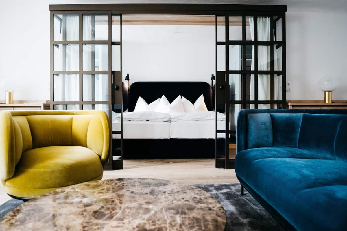Un dormitorio moderno con una cama, un sillón amarillo y un sofá azul.
