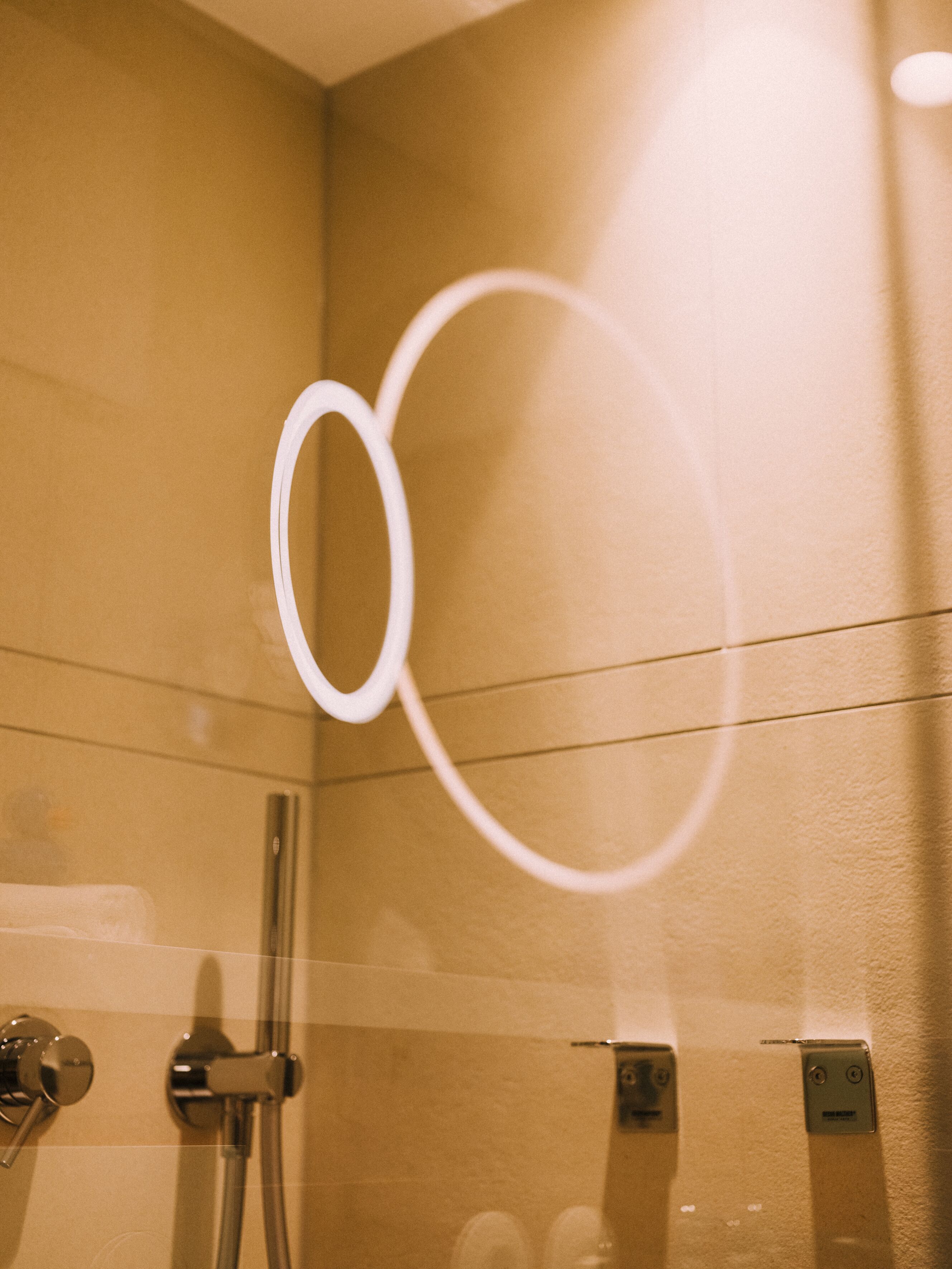 Une salle de bain avec une douche à parois de verre, un porte-serviettes rond blanc et un porte-serviettes mural.