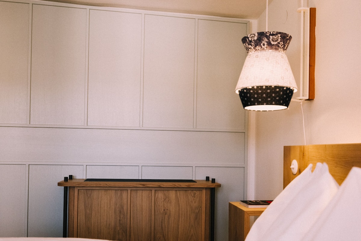 Una habitación de hotel con cabecera de madera, una mesita de noche y una lámpara.