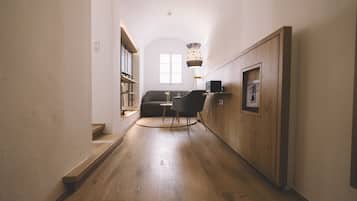 Un pasillo con piso de madera, un sofá, una silla y una lámpara.