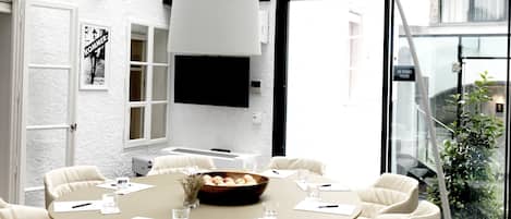 A modern dining area with a glass ceiling, white walls, and a round table surrounded by chairs.