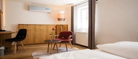 Ein Hotelzimmer mit einem Bett, einem Schreibtisch, zwei Stühlen, einer Lampe und einem Fenster.