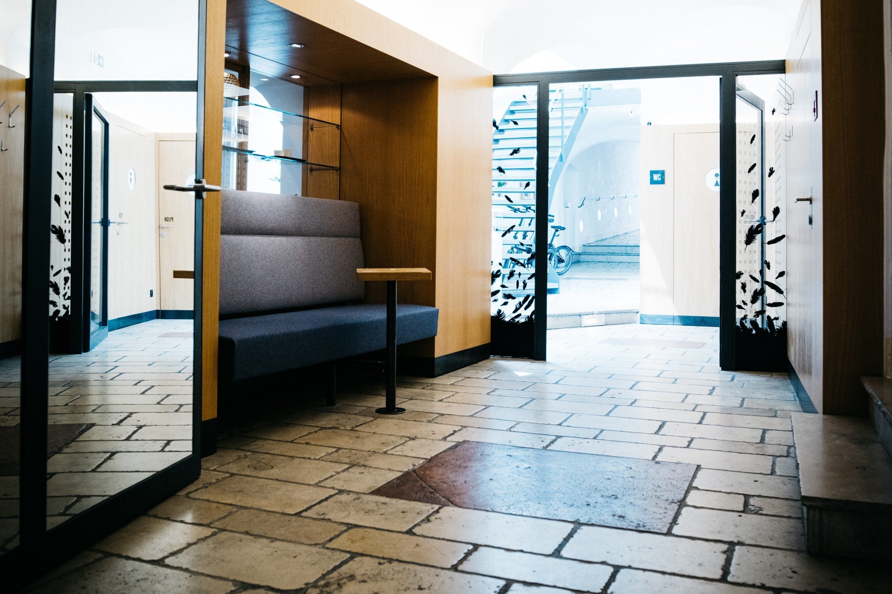 Eine moderne Lobby mit einer Bank, einer Treppe und einer Tür zu einem weiteren Bereich.