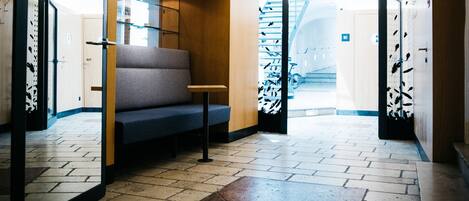 Eine moderne Lobby mit einer Bank, einer Treppe und einer Tür zu einem weiteren Bereich.