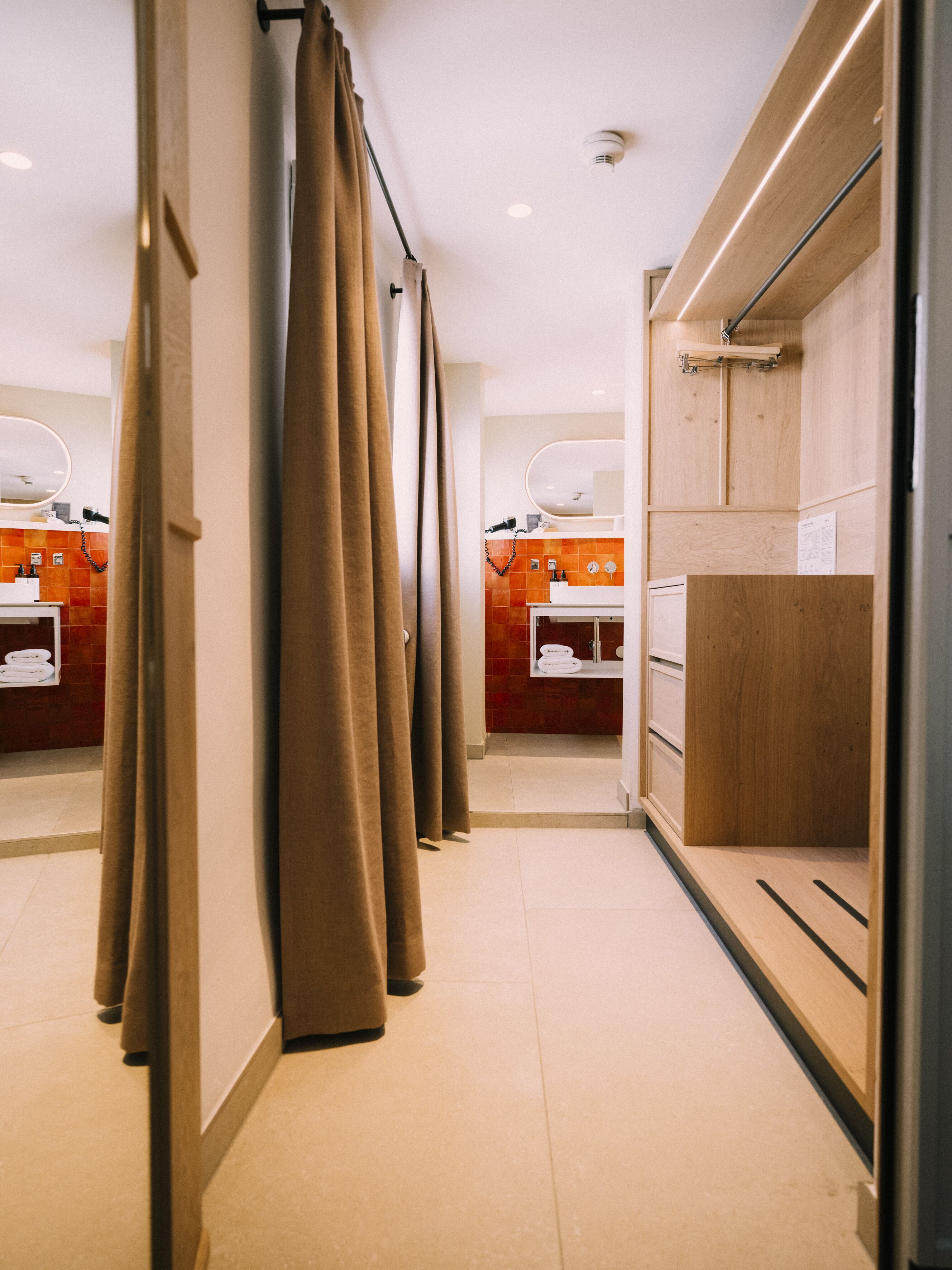 A modern bathroom with wooden cabinets, a mirror, and a shower area.
