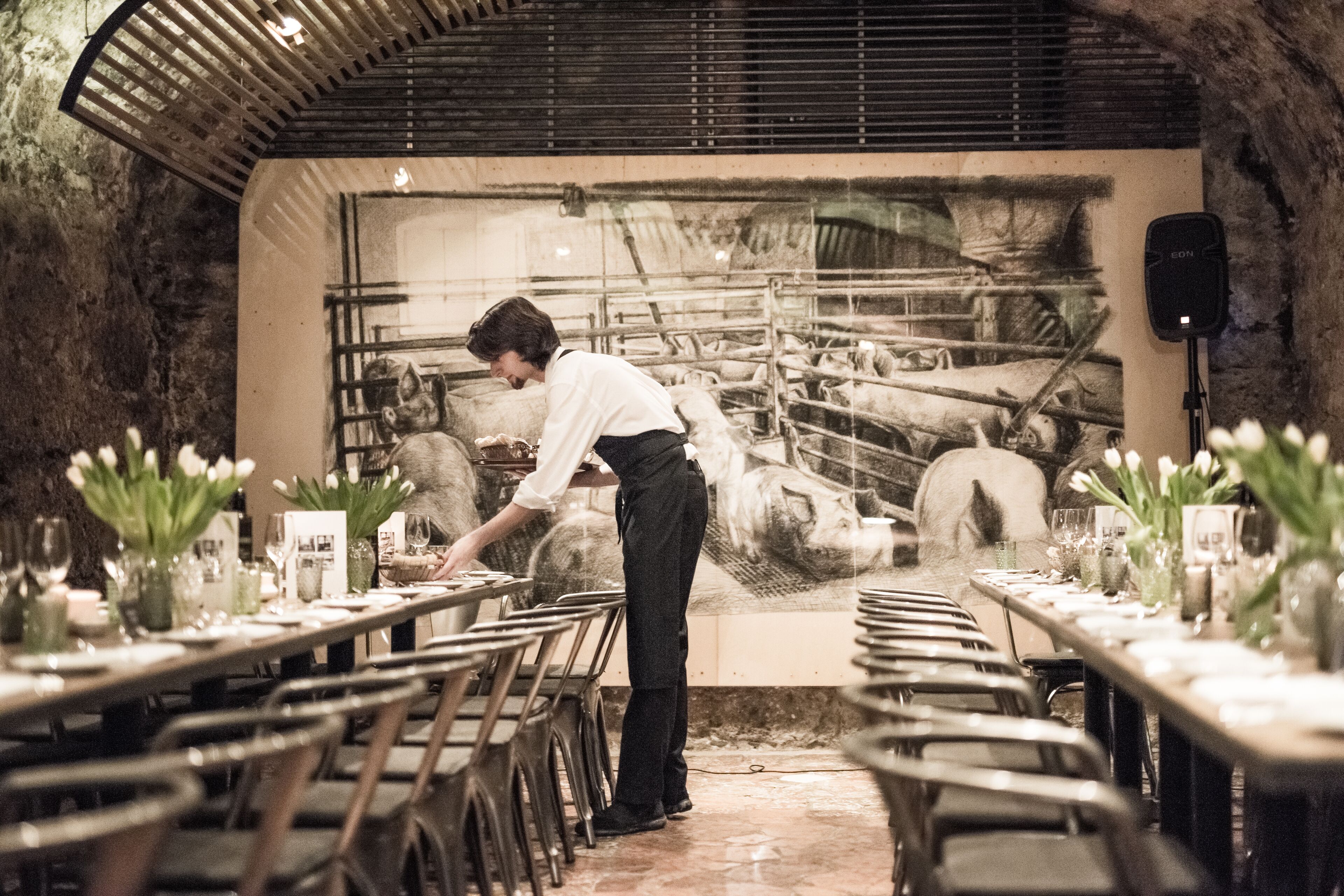 A restaurant with a rustic interior, featuring a long dining table set for a meal, surrounded by chairs.