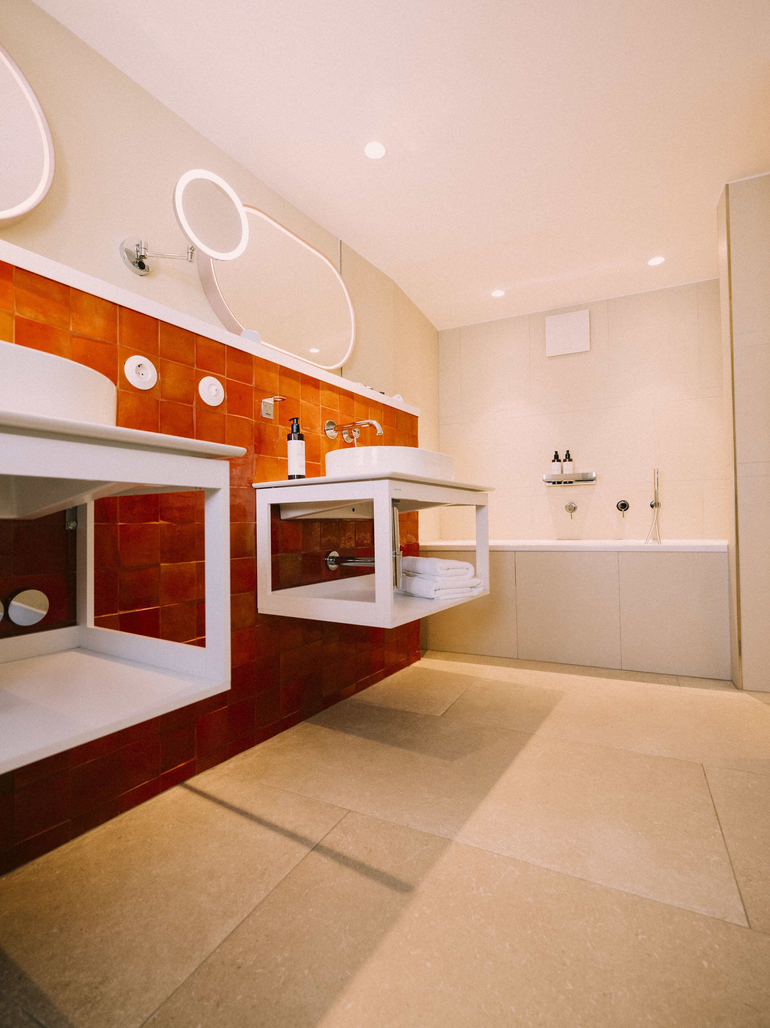 Un baño moderno con dos lavamanos, un espejo grande y una bañera.