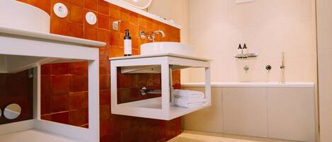 Un baño moderno con dos lavamanos, un espejo grande y una bañera.