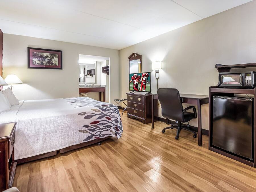 Quarto de hotel com cama, escrivaninha, cadeira e minibar.