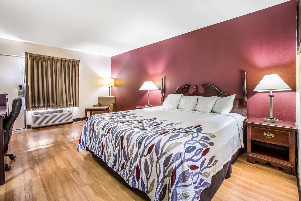 Habitación de hotel con una cama grande, dos mesitas de noche con lámparas, un escritorio y un equipo de aire acondicionado.