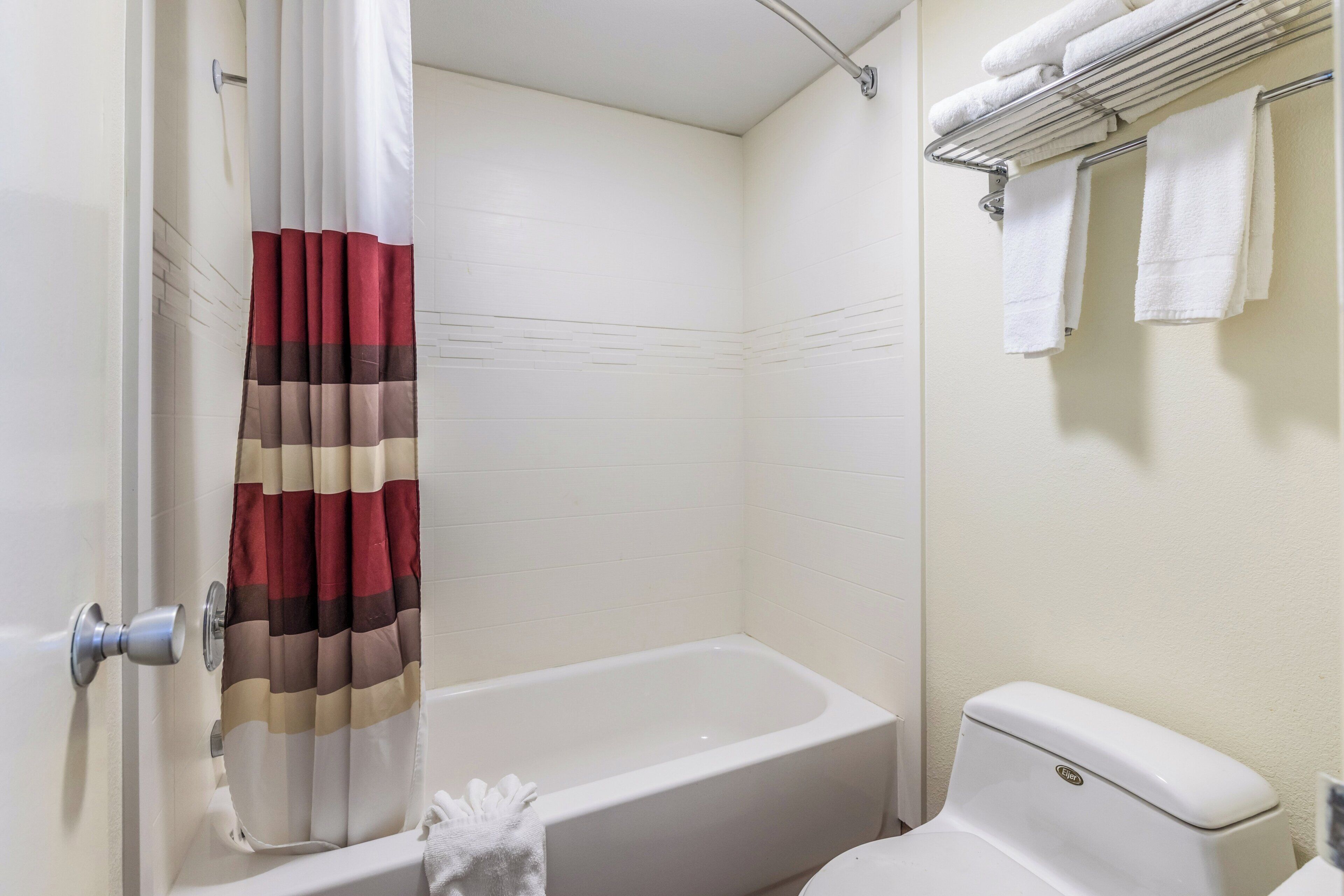 Un baño con bañera, inodoro y perchero para toallas.