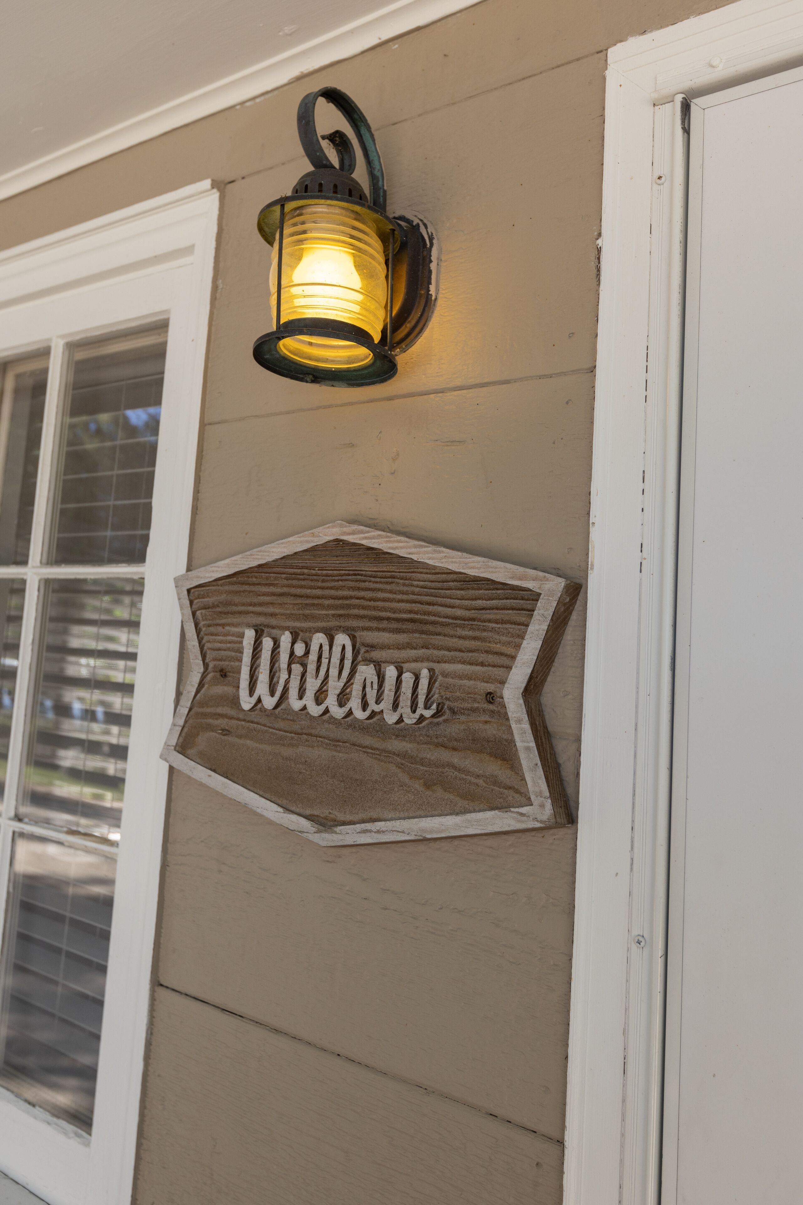 A house exterior with a lit lantern and a wooden sign that reads "Willow."