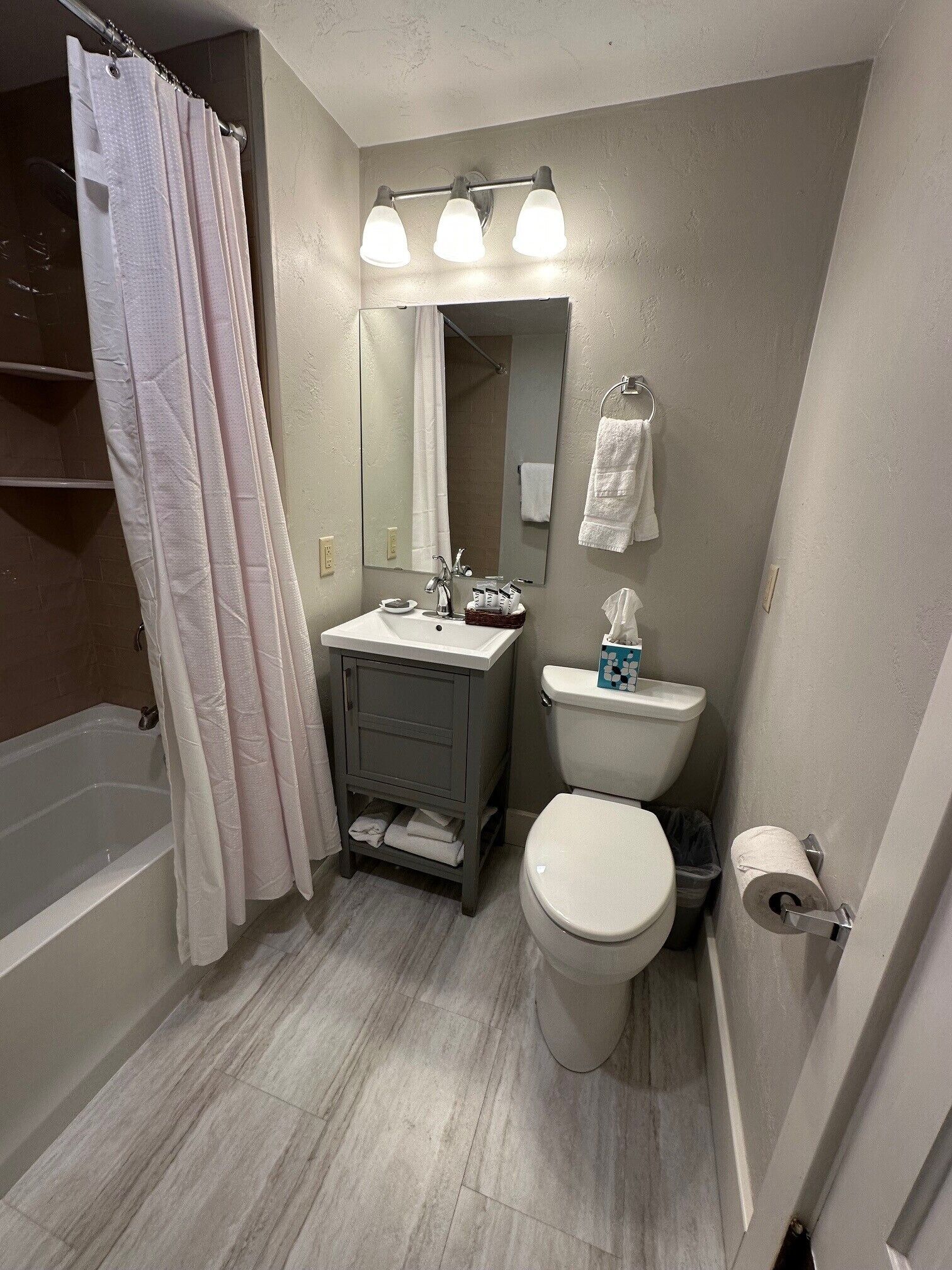 Une salle de bain équipée d’une baignoire, de toilettes, d’un lavabo et d’un miroir au-dessus du lavabo.